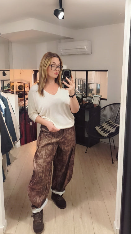 Pantalon barrel imprimé militaire marron porté avec un pull fin écrue. 