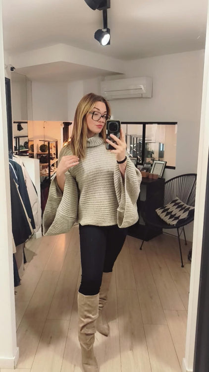 Fuseau noir porté avec un pull poncho et des bottes. 