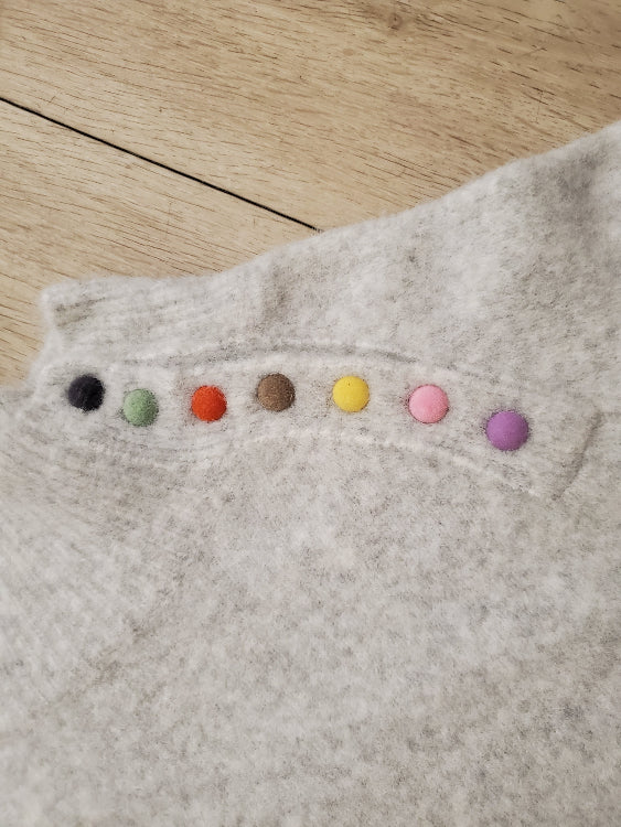 Pull gris chiné col montant avec boutons multicolore. détails boutons.