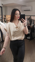 Top en satin avec un col drapé. manches courtes. photo porté. colorie gold. article rentré dans le pantalon pour structurer la silhouette. 