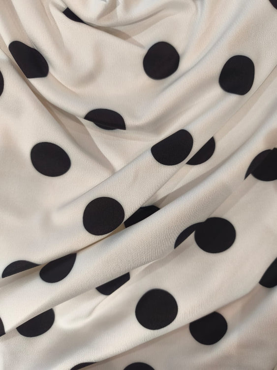 Top asymétrique drapé laissant apparaitre une épaule. colorie blanc a pois noir. photo détail.