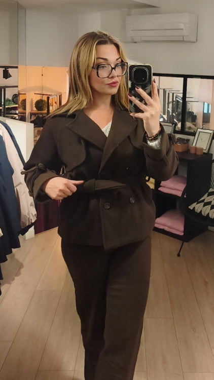 Manteau trench court colorie marron porté avec un jean droit marron. 