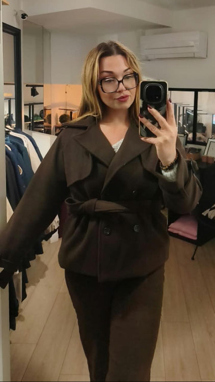 Manteau trench court colorie marron porté avec un jean droit marron. 