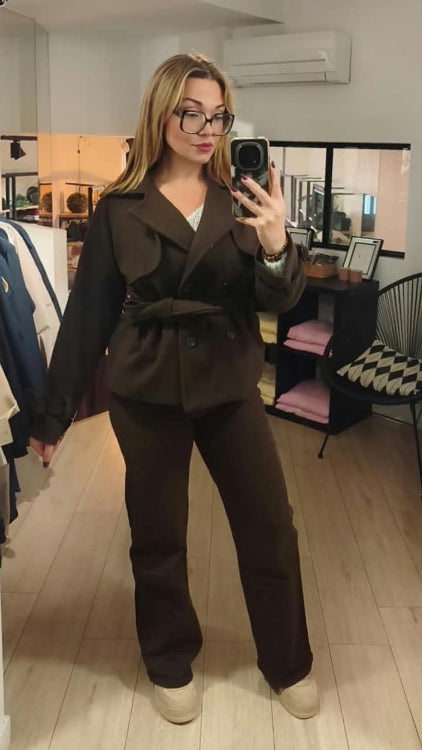 Manteau trench court colorie marron porté avec un jean droit marron. 