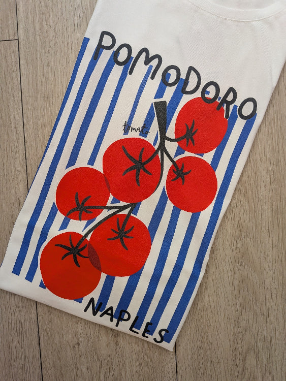 T-shirt imprimé d'une grappe de tomate sur un fond de rayures bleu foncé. Photo plié