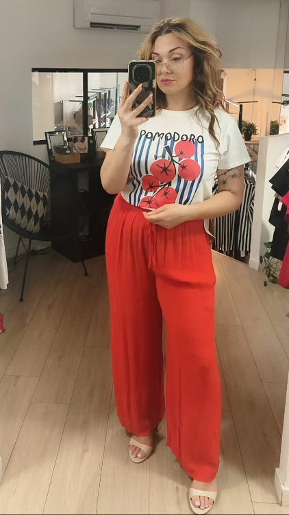 T-shirt imprimé d'une grappe de tomate sur un fond de rayures bleu foncé. Photo porté avec un pantalon fluide corail. 