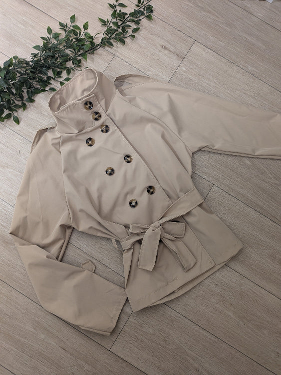 trench court beige. photo a plat, boutonné jusqu'en haut. 