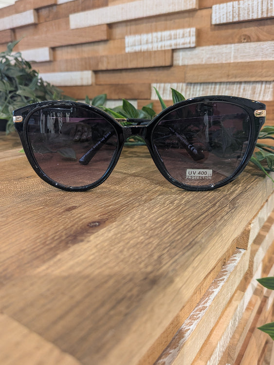 Lunettes de soleil ronde légèrement papillon. colorie noir. 