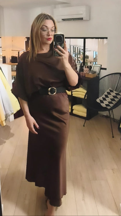 Jupe longue en satin marron porté avec une ceinture et un top en satin manche 3/4 marron. 