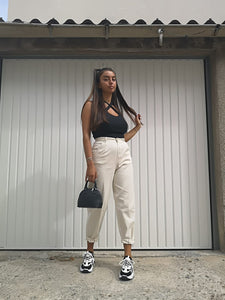 Top a bretelles croisées noir porté avec une pantalon de toile beige coupe mum, des baskets et un petit sac