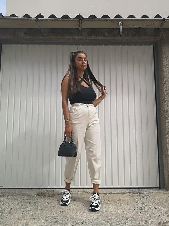 Top a bretelles croisées noir porté avec une pantalon de toile beige coupe mum, des baskets et un petit sac