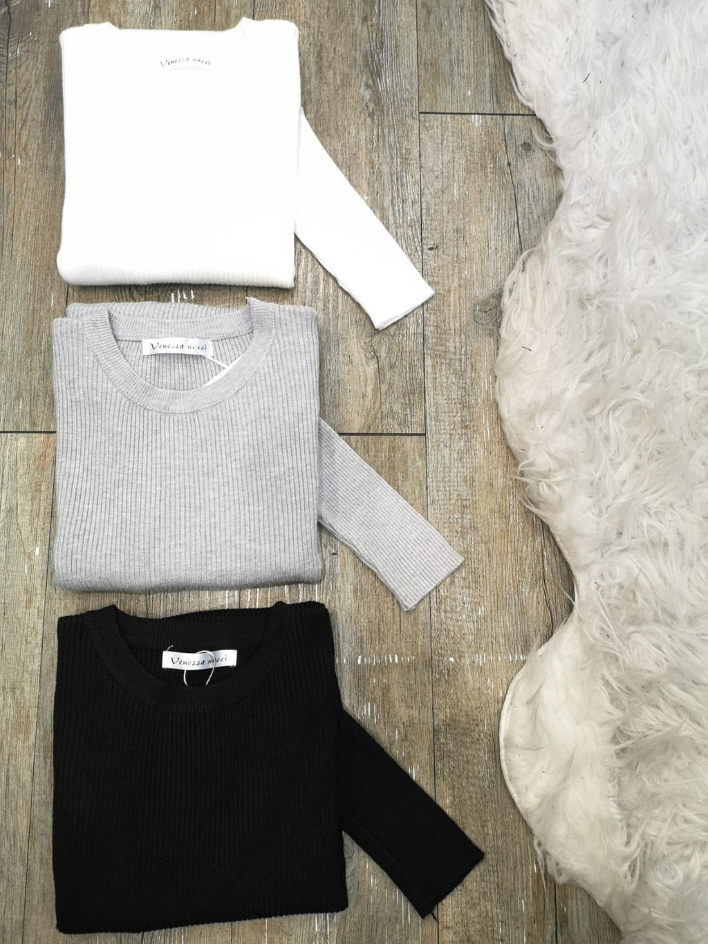 Photo a plat plié des différentes couleur dans le pull col rond basic. De haut en bas Blanc, Gris, Noir