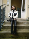 Veste bi matière blanche et noir porté avec un jean enduit noir, un sac en fausse fourrure et des bottines fourrées