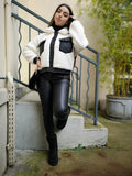Veste bi matière blanche et noir porté avec un jean enduit noir, un sac en fausse fourrure et des bottines fourrées