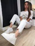 Jean délavé troué porté avec in T-shirt imprimé et des baskets.